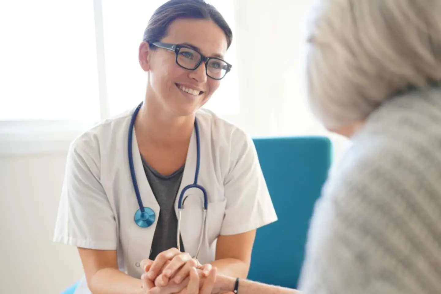 Um médico sorridente está segurando a mão de um paciente idoso, serviços nativos da AWS para melhorar a segurança