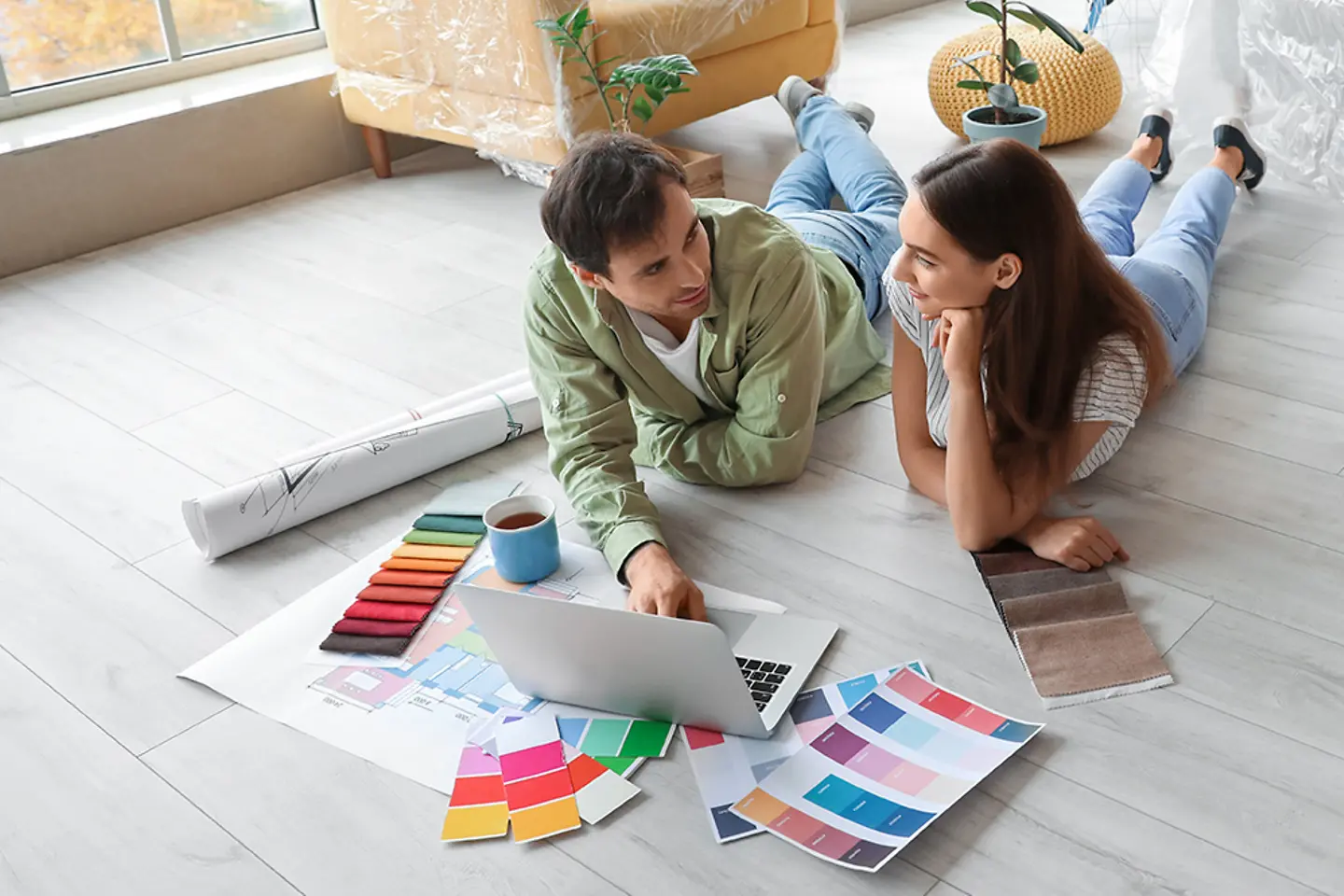 Young couple renovating flat, choosing online floorboards and wallpaper.