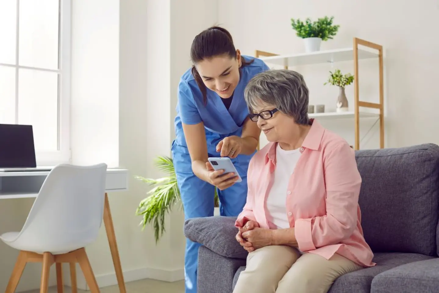 Enfermera enseñando a una mujer mayor a usar una app móvil de salud