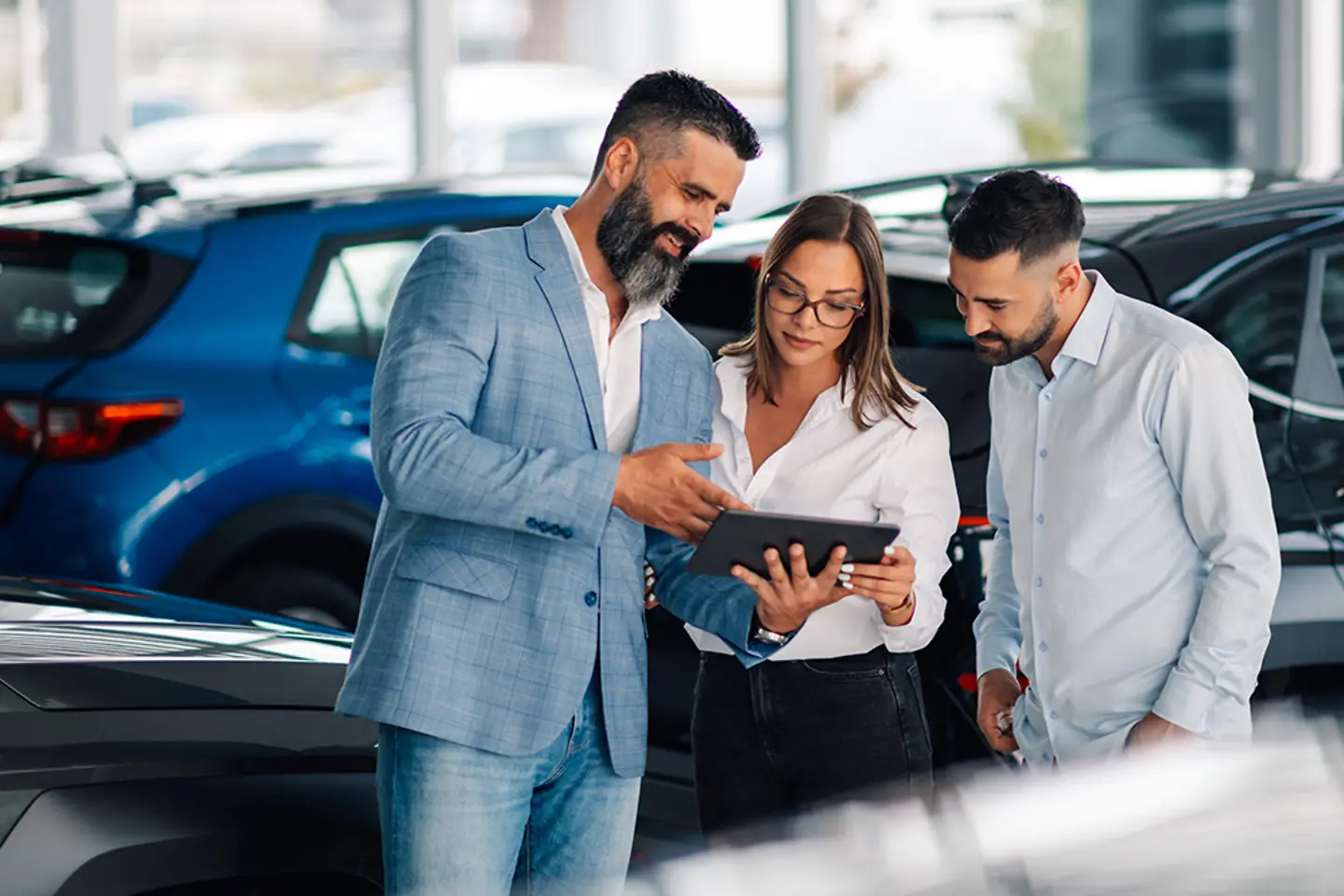 Vendedor usando una tableta para mejorar el proceso de compra de un coche por parte de una pareja