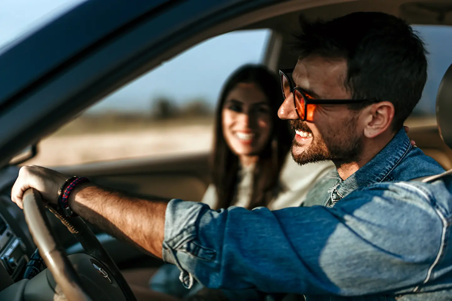 Pareja feliz conduciendo juntos en un coche, disfrutando de una puesta de sol escénica en una carretera 