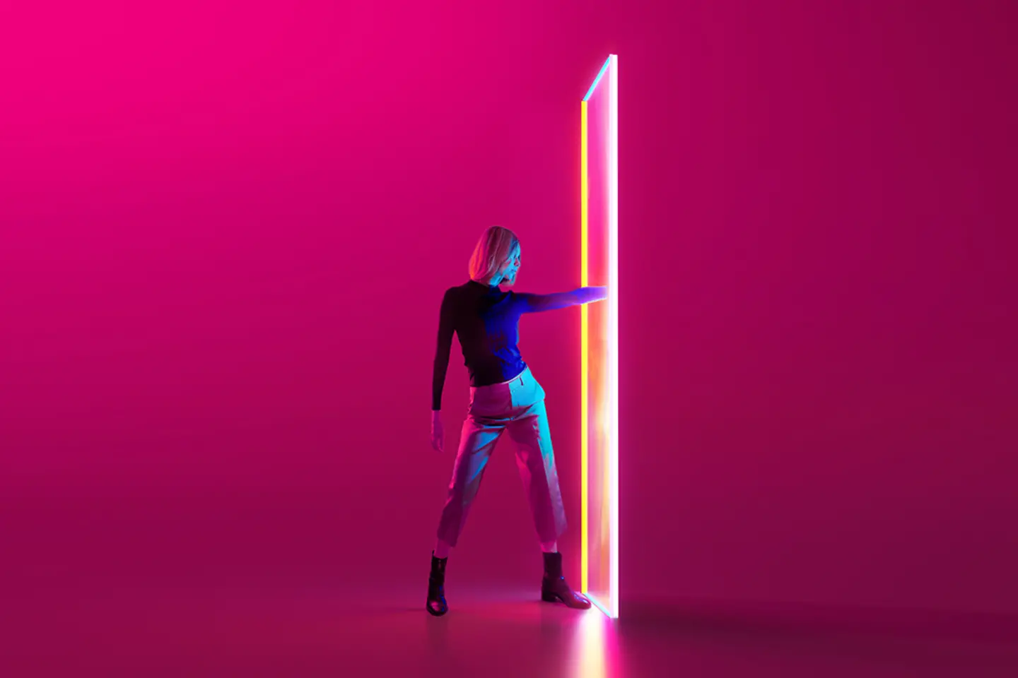 Digital generated image of young woman standing on red background and putting hand into multicolored glowing portal door.abrka