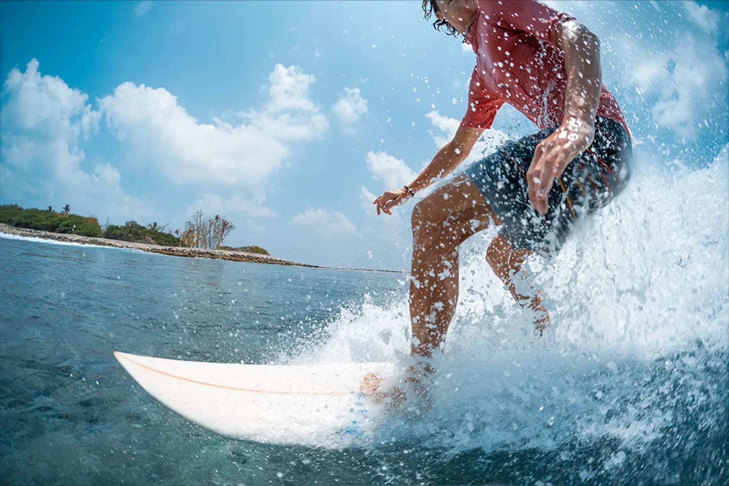 Young caucasian man surfs the ocean wave and makes a lot of splashes into the camera