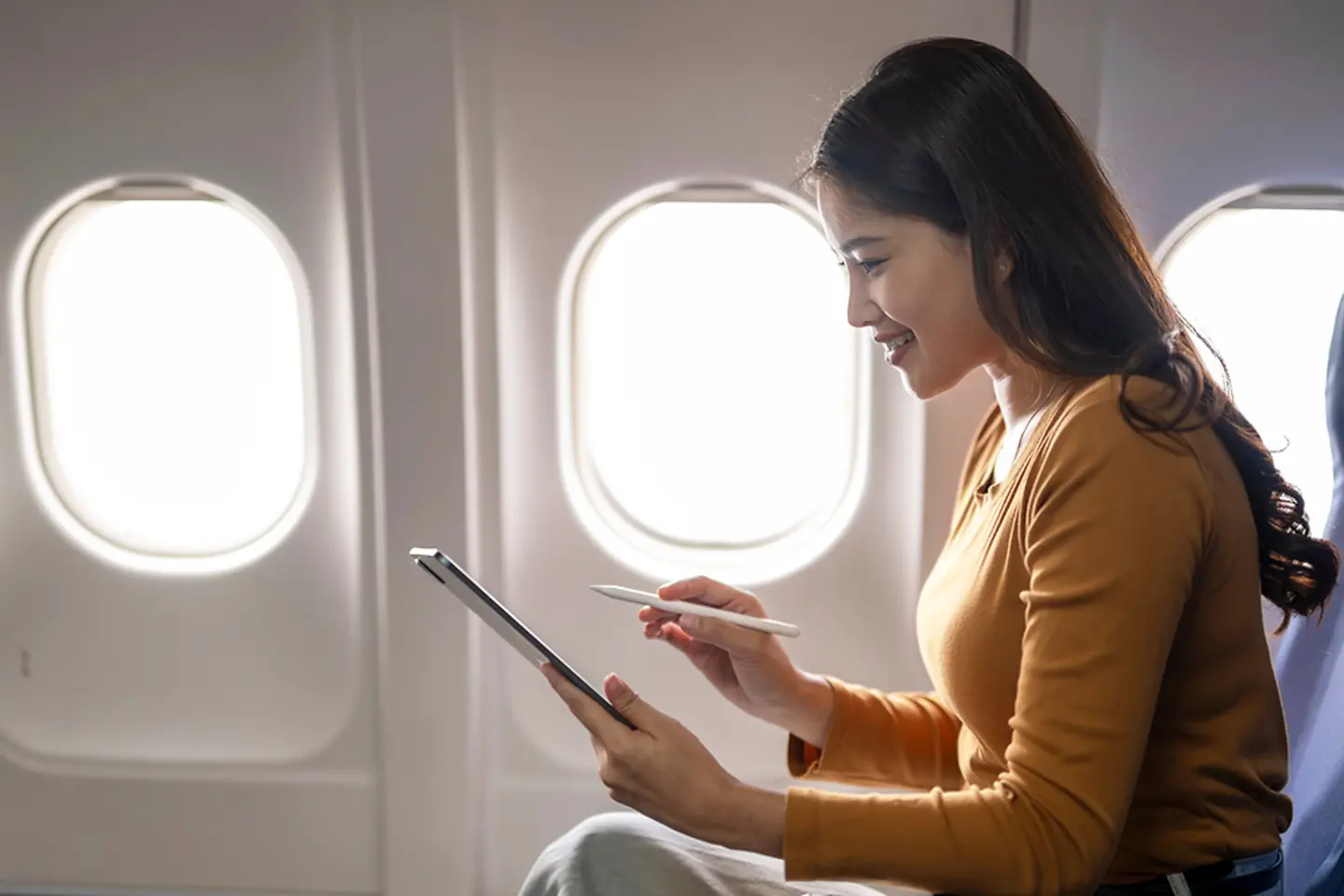 Jovem empresária trabalhando em um tablet em um avião