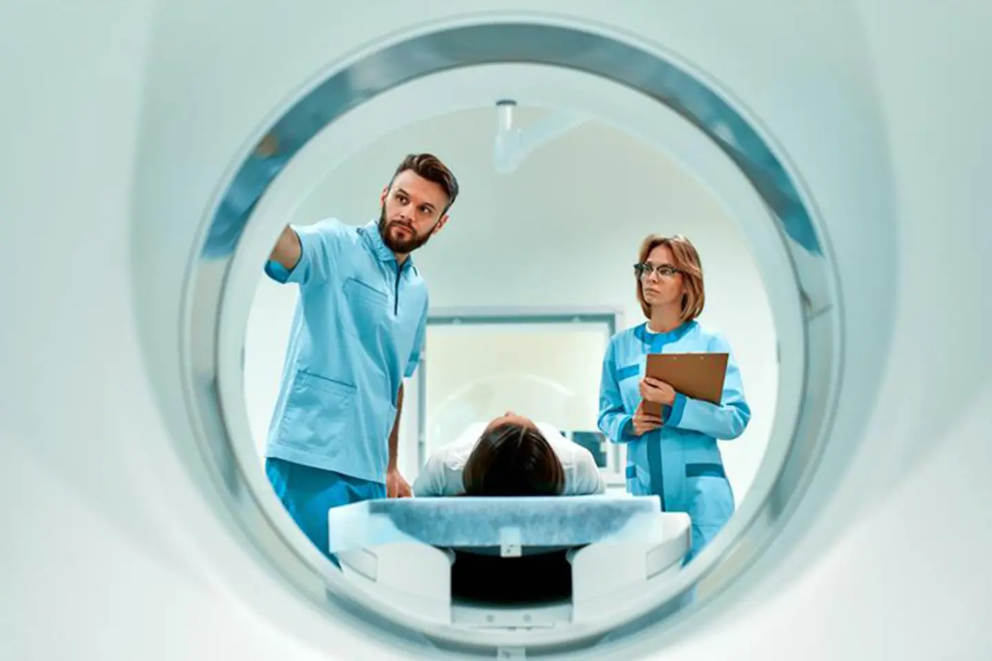 Zwei Ärzte überwachen einen Patienten, der in ein CT-Gerät fährt.