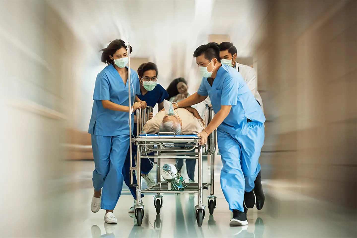 Ein Team von Ärzten rennt mit einem Patienten auf einer Rolltrage in der Notaufnahme